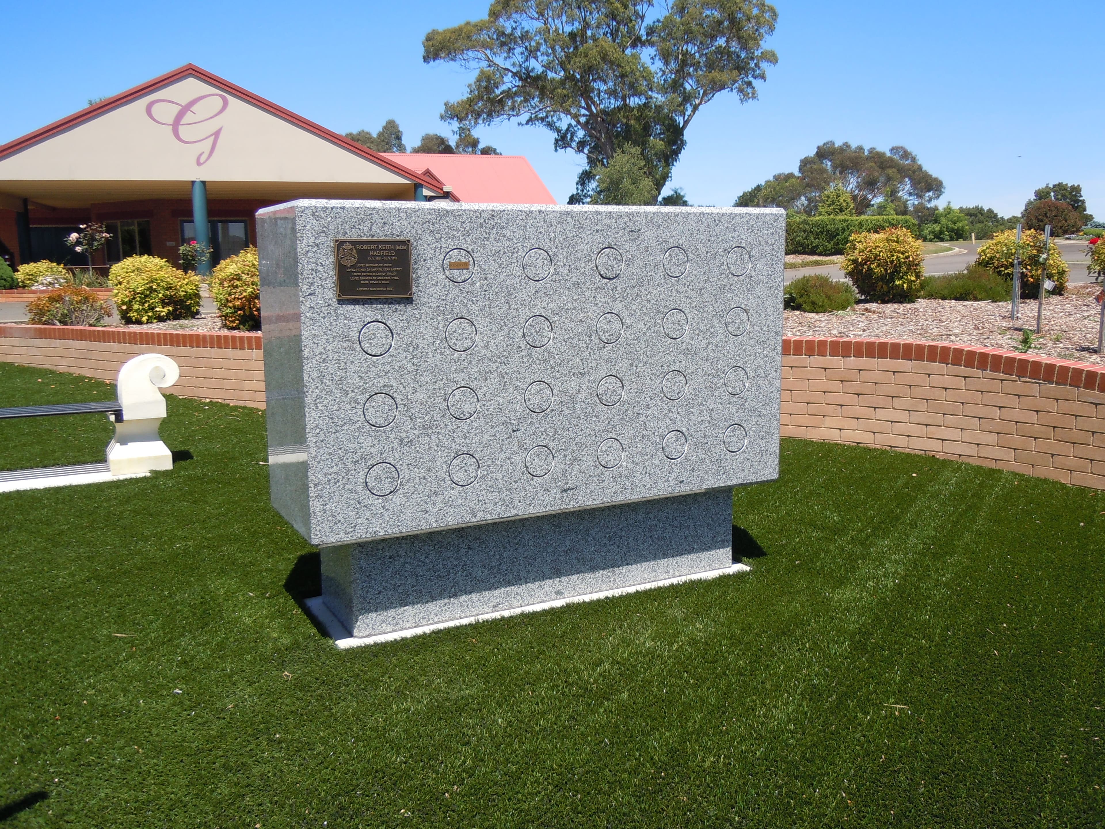 A freestanding granite wall niche memorial with individual niche plaques