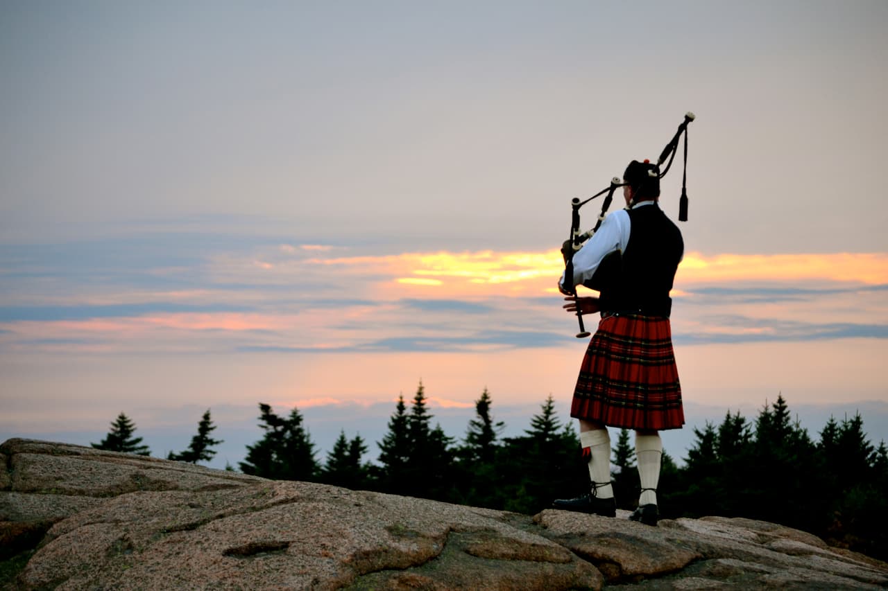 A lone bagpiper playing at sunset