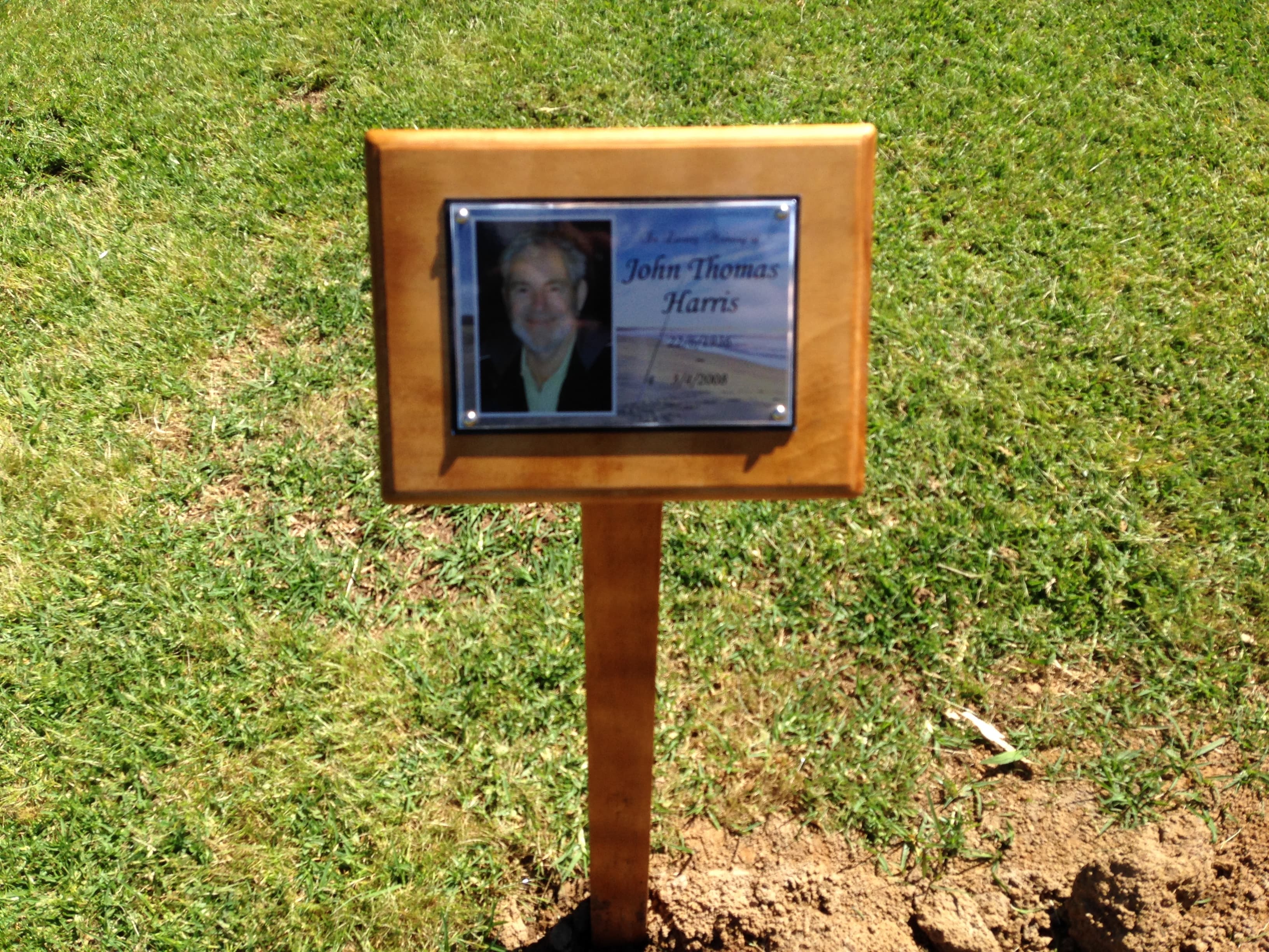 A timber temporary grave marker with a photo and nameplate