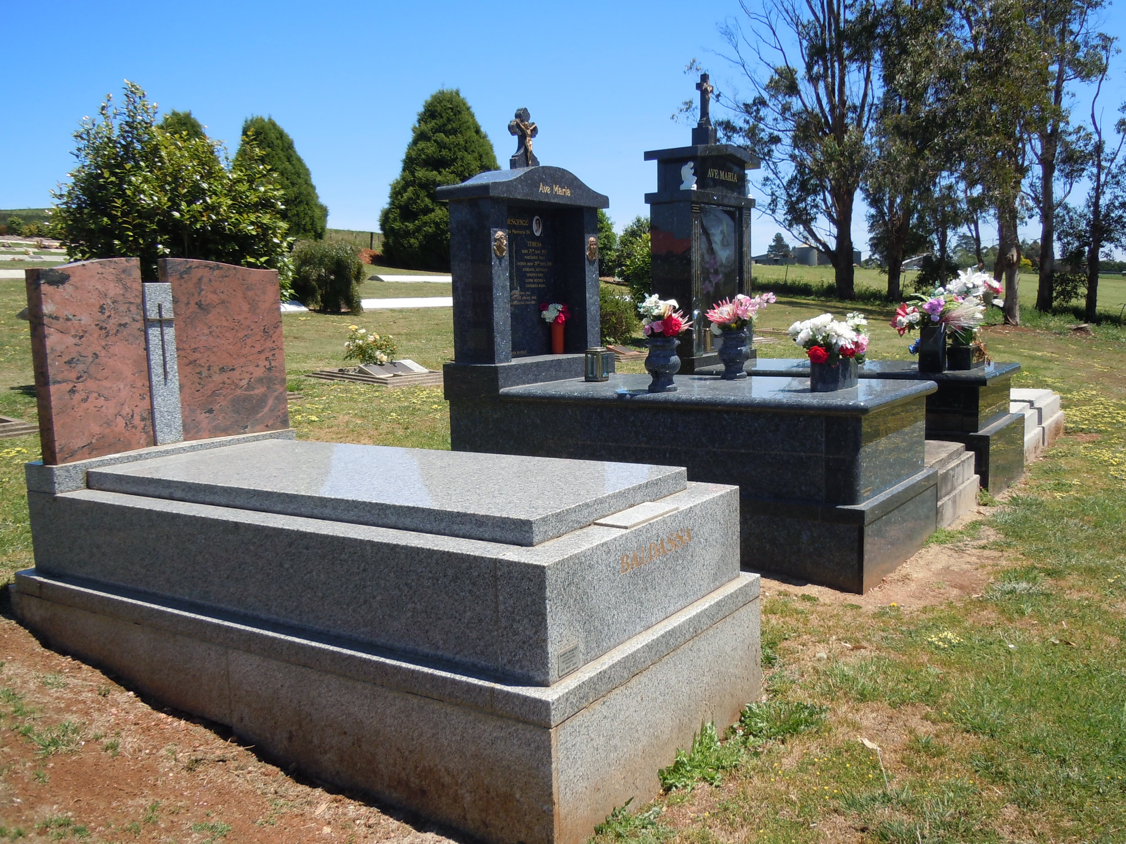 Elaborate granite monuments with crosses and floral tributes