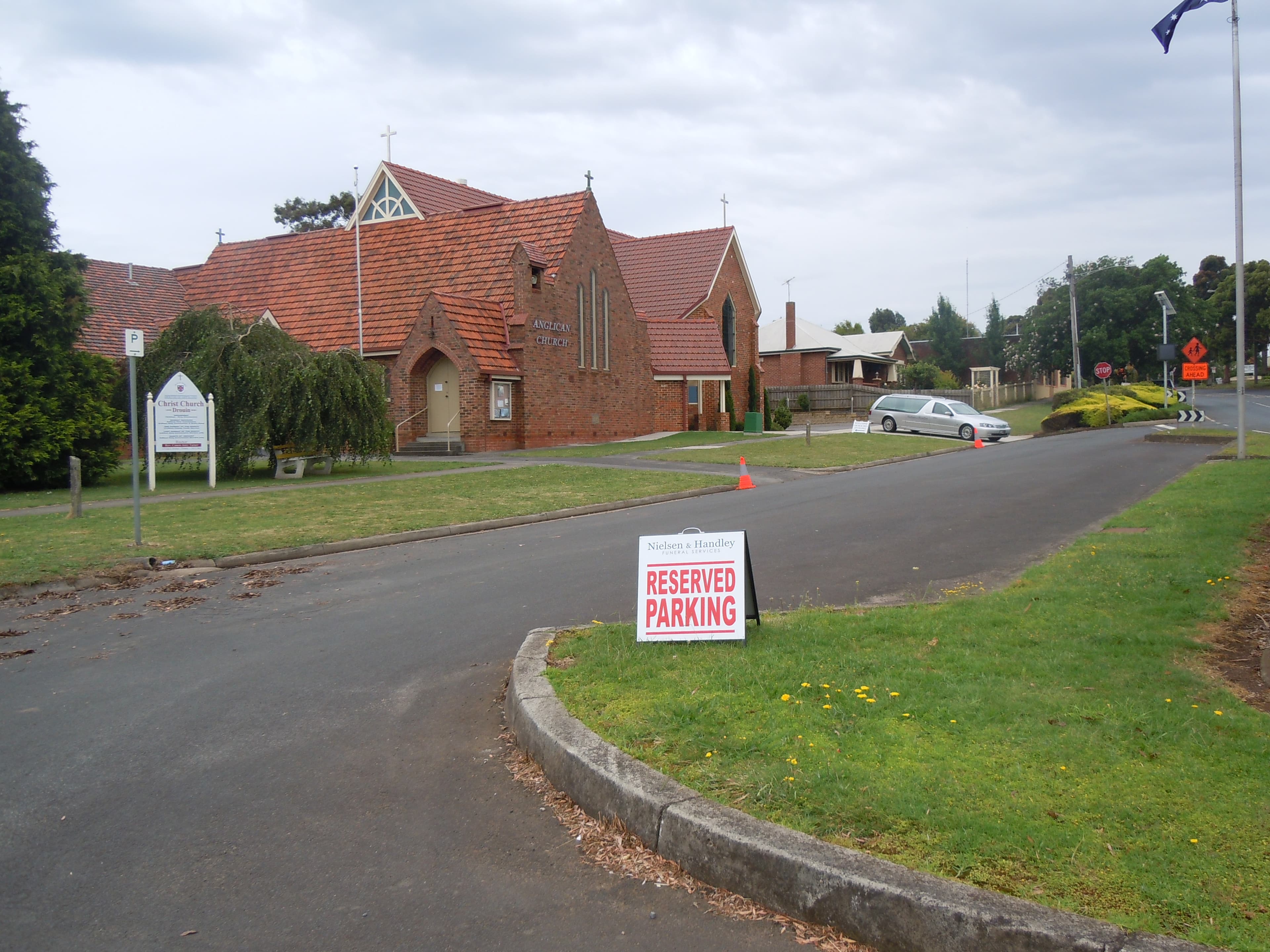 Christ Church, Drouin, with a Nielsen Funerals hearse parked outside