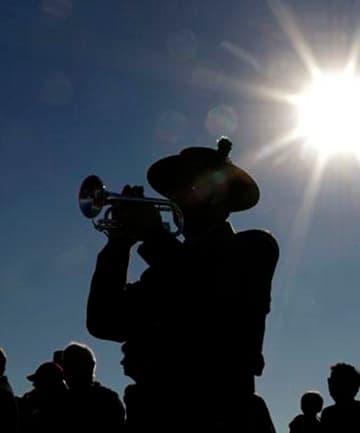 A bugler playing the Last Post silhouetted against the sky