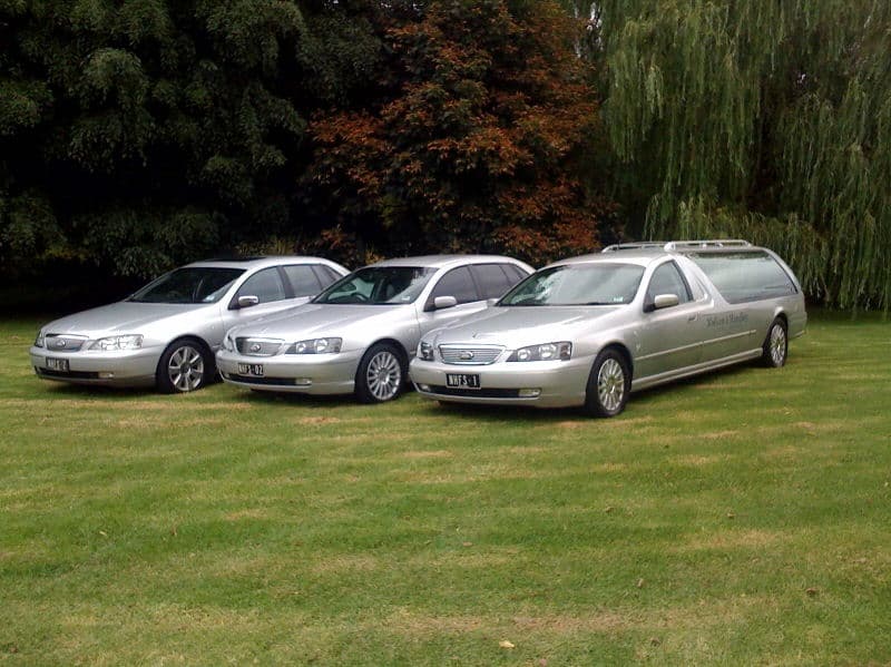 Nielsen Funerals' fleet of silver vehicles, including the hearse