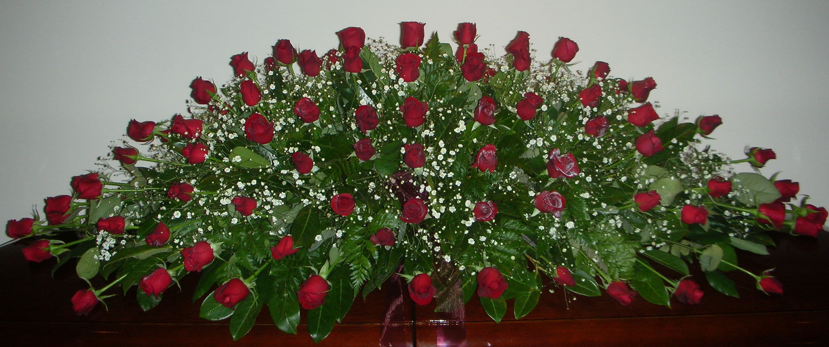 Red roses with gypsophila and fern casket spray