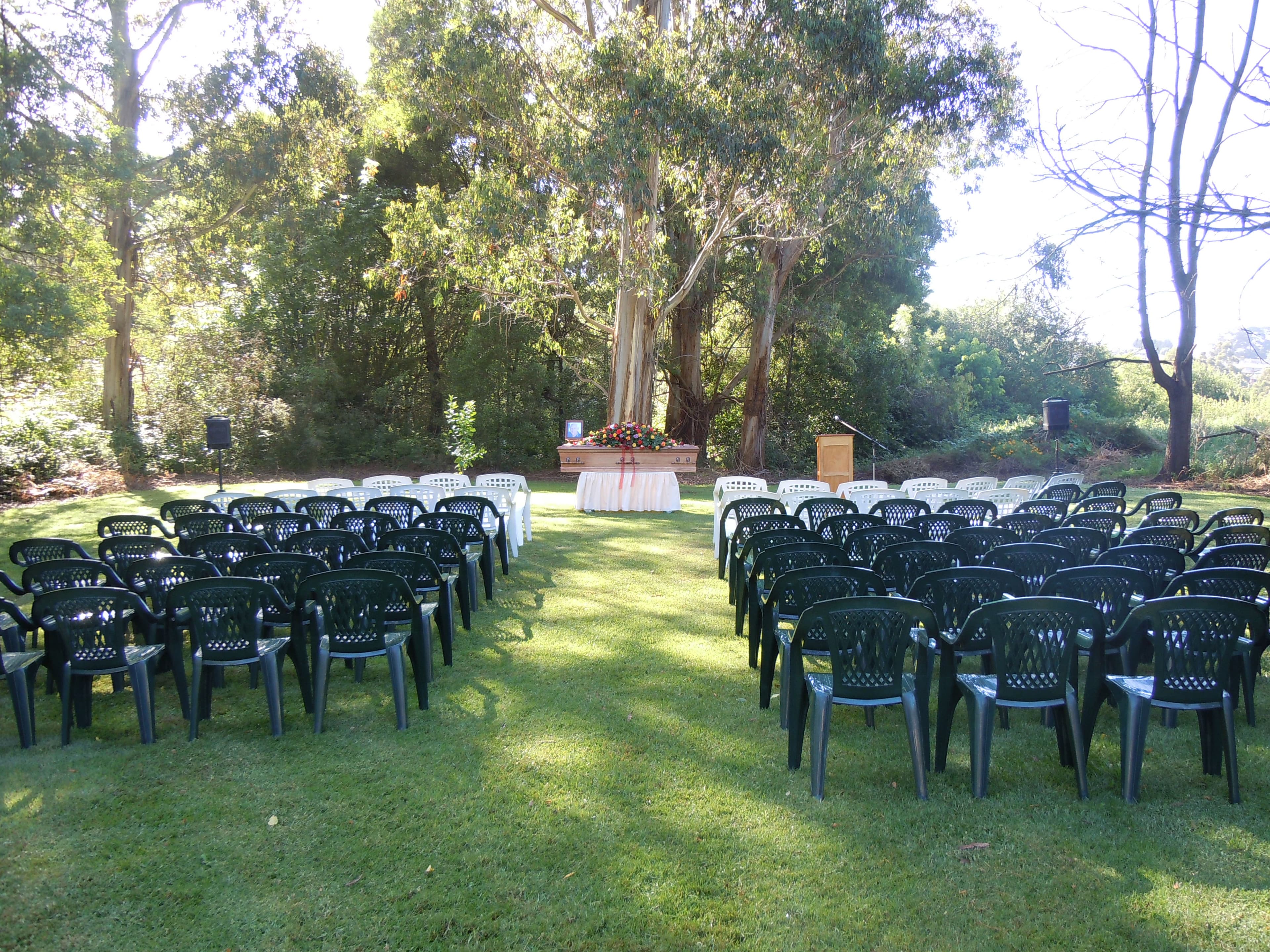 An outdoor memorial garden set up with rows of chairs for a funeral service